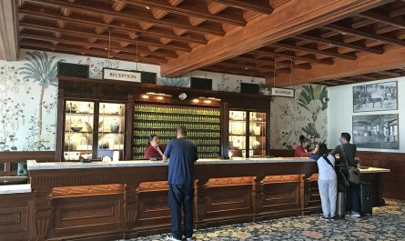 Guests at the reception desk of a hotel lobby with a carved wooden ceiling