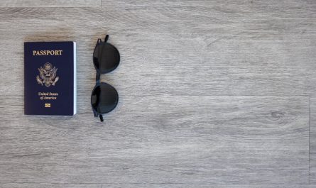 A U.S. passport and a pair of sunglasses on a gray wooden surface